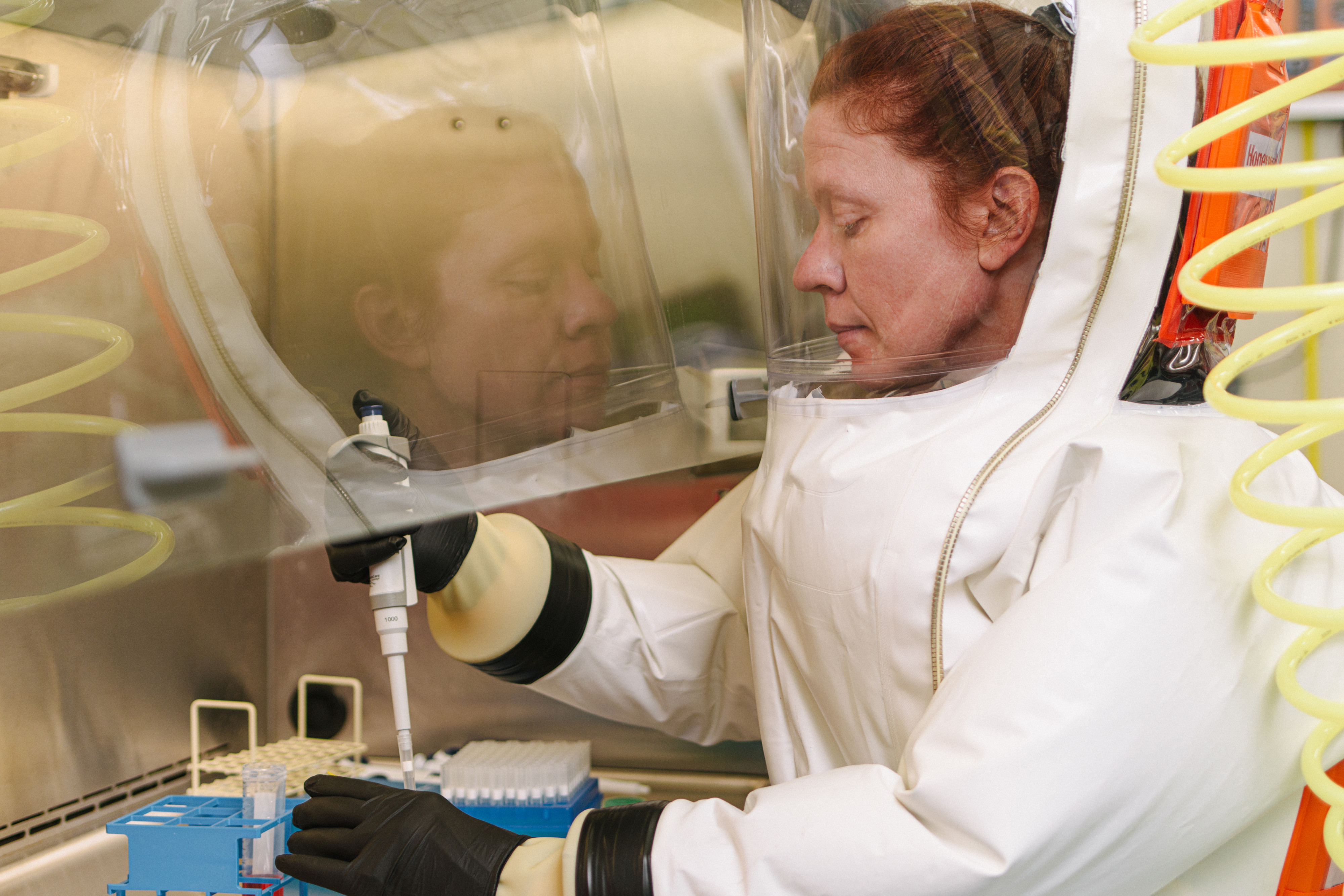 woman in hazmat suit putting samples in vials
